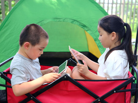 Two kids playing with tablets high quality photoの写真素材