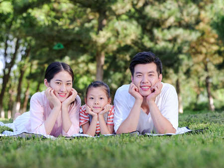 Happy family of three on the park grass high quality photoの写真素材