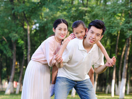 Happy family of three playing in the park high quality photoの写真素材
