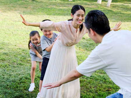 Happy family of four playing in the park high quality photoの写真素材