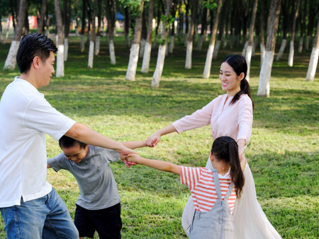 Happy family of four playing in the park high quality photoの写真素材