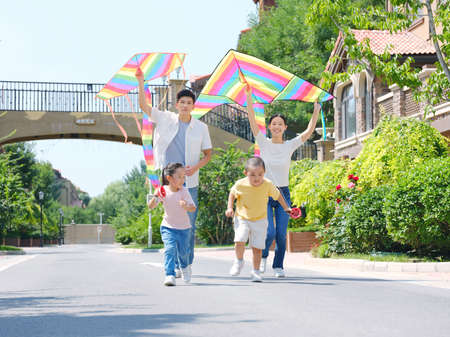 Happy family of four flying kites outdoors high quality photoの写真素材