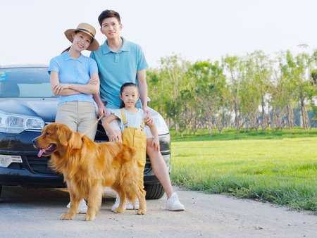 Happy family of three and pet dog in parking lot high quality photoの写真素材