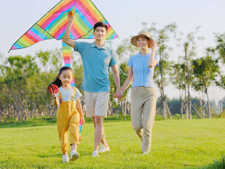 Happy family of three flying kites in the park high quality photoの写真素材