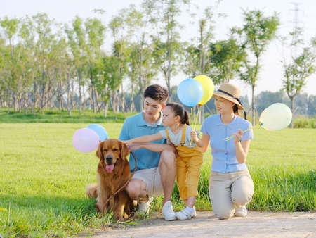 Happy family of three and pet dog in the park high quality photoの写真素材