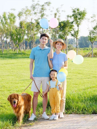 Happy family of three and pet dog in the park high quality photoの写真素材