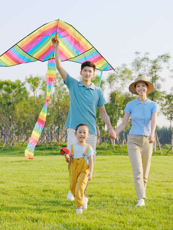 Happy family of three flying kites in the park high quality photoの写真素材