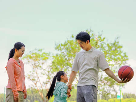 Happy family of three playing basketball in the park high quality photo