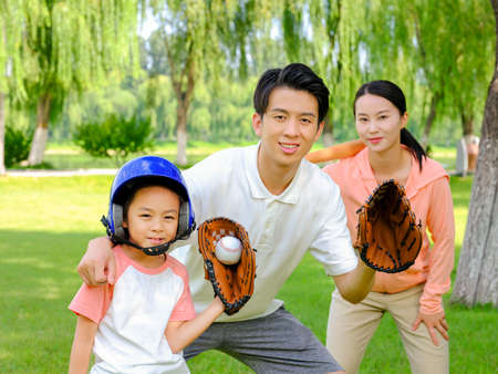 Happy family of three playing baseball in the park high quality photoの写真素材