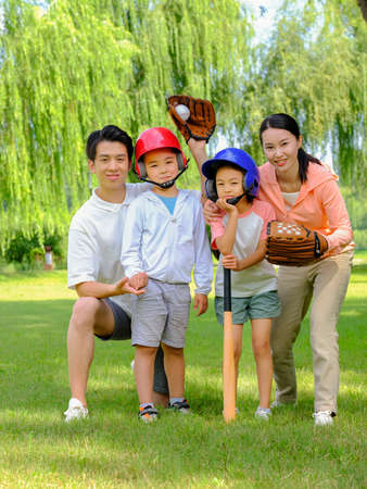 Happy family of four playing baseball in the park high quality photoの写真素材
