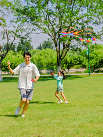 Happy father and daughter are flying kites in the park high quality photoの写真素材