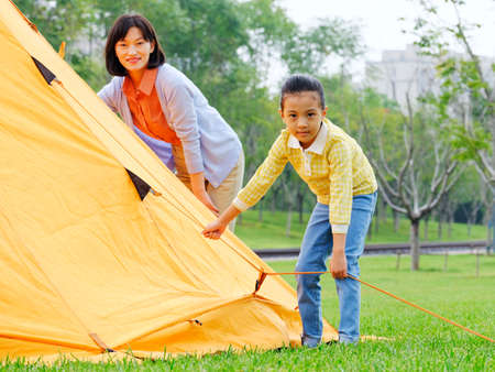 The happy mother and daughter set up a tent outdoors high quality photoの写真素材