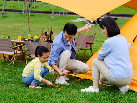 A happy family of three set up tents outdoors high quality photoの写真素材