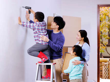 A happy family of four decorates their house high quality photoの写真素材