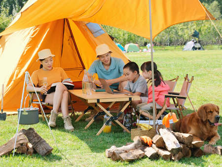 Happy family of four and dog camping out high quality photoの写真素材