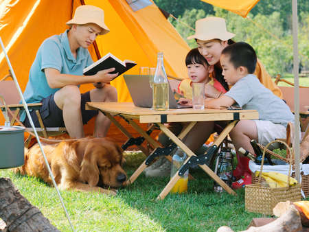 Happy family of four and dog camping out high quality photoの写真素材