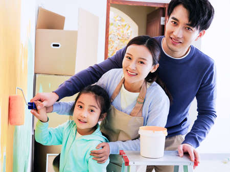 A happy family of three painting walls high quality photoの写真素材