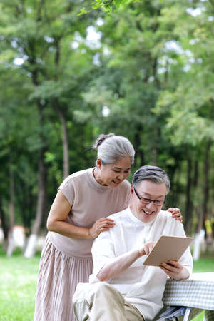 Happy elderly couples use tablet computers to surf the Internet outdoors high quality photoの写真素材