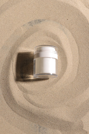 White jar of cream on sand background. Top view, copy spaceの写真素材