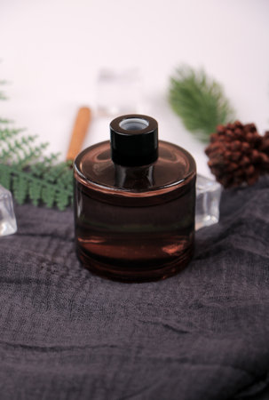 Bottle of perfume on a black tablecloth with pine cones.