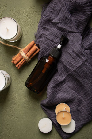 Aromatherapy oil with cinnamon and candles on a green backgroundの写真素材