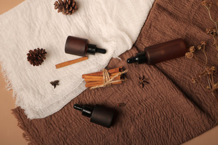 Spa composition with aroma oil, cinnamon sticks and towel on brown background