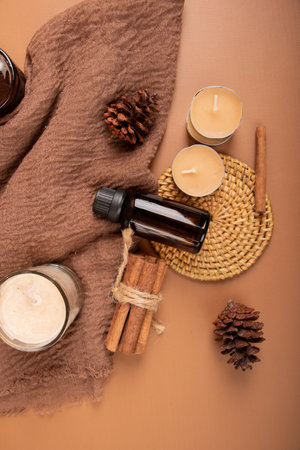 Spa still life. Aromatherapy oil, cinnamon sticks, candles and towel on brown backgroundの写真素材