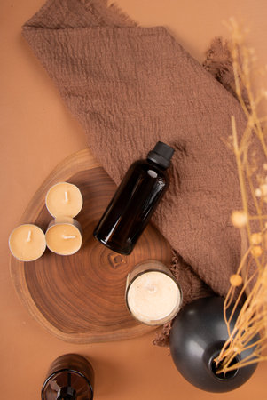 Spa still life with oil bottle, candles and towel on brown background