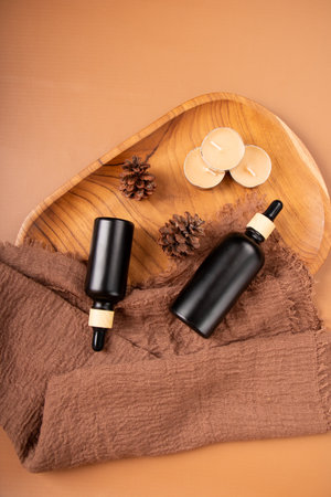 Essential oil in a black bottle on a wooden tray with a towelの写真素材