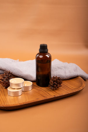 Spa still life with essential oil, candles and towel on brown background