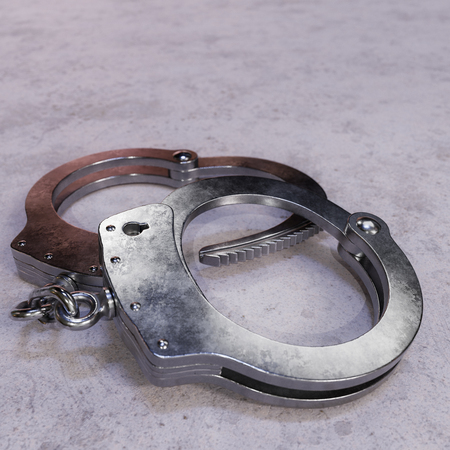 Pair of high security handcuffs resting on an uninviting concrete surface.の写真素材