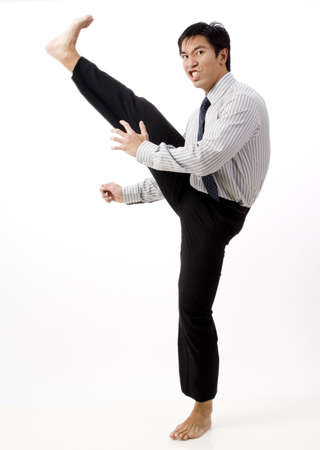 A young asian businessman looks tough doing a karate kickの写真素材