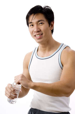 A fit young asian man in sports vest with bottle of waterの写真素材