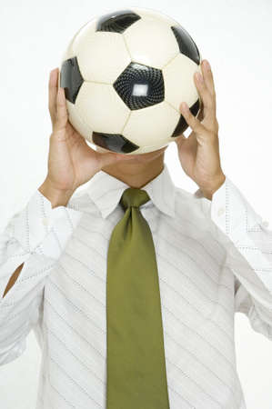 A young man replaces his head with a soccer ballの写真素材