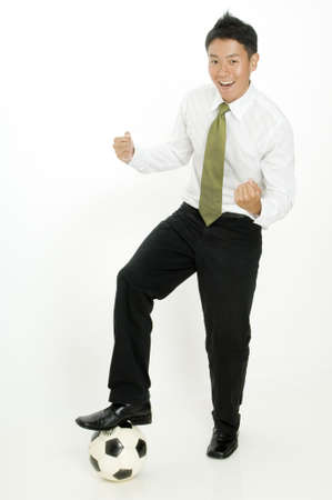 A young businessman celebrates as he steps on a ballの写真素材