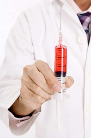 A young doctor holds aloft a large syringeの写真素材