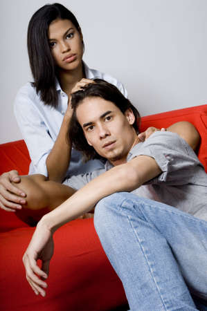 A young couple sitting on the floor and sofaの写真素材