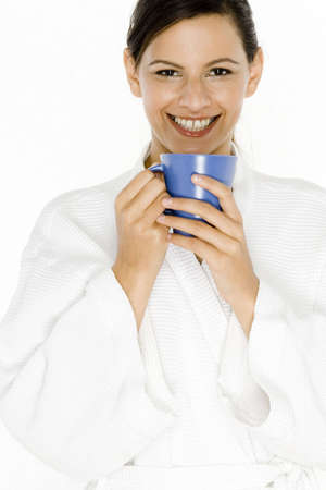 A pretty young woman in a white robe with a blue mugの写真素材