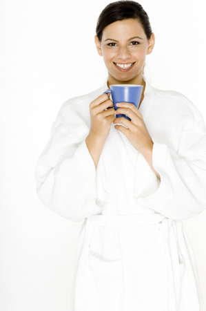 A beautiful young woman in a robe with a blue mugの写真素材