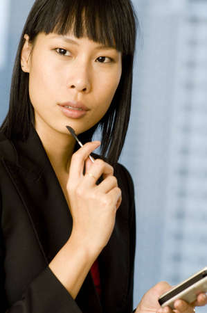 A young asian businesswoman holding a PDA with stylus (shallow depth of field)の写真素材