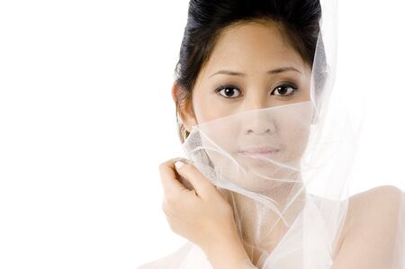 A beautiful asian woman holding her veil across her face on white backgroundの写真素材
