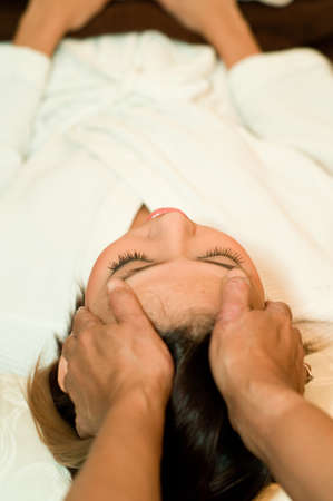 A young Asian woman having her head massaged by a therapistの写真素材
