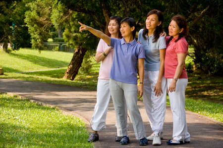 A group of Asian women standing together in the park looking at something of interestの写真素材