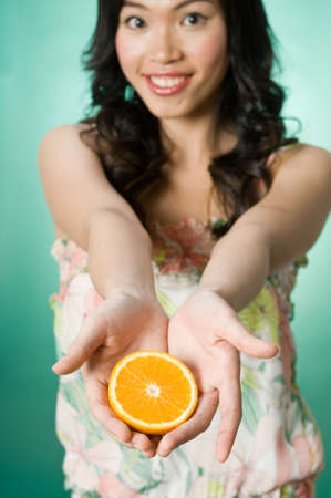 A model posing in a summer dress with an orangeの写真素材