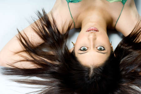 A beautiful woman in green dress lying on studio floorの写真素材