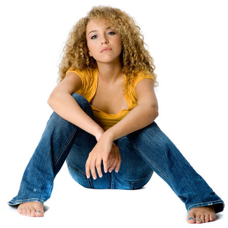 A pretty teenage girl in yellow top and jeans on white backgroundの写真素材