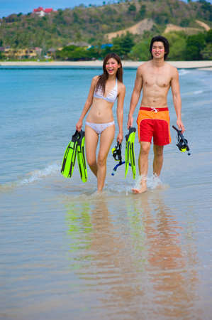A young couple with snorkelling gear on a tropical beachの写真素材