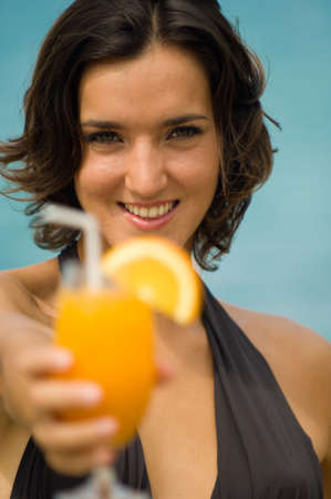 A young woman on the beach with a glass of orange juiceの写真素材