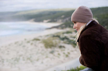 A young attractive woman standing overlooking a stretch of coastlineの写真素材