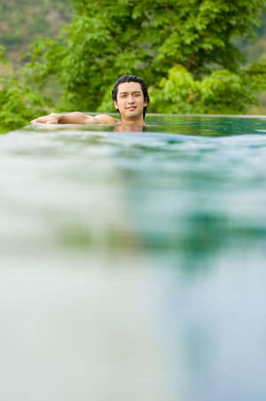 A young man relaxing in a swimming poolの写真素材